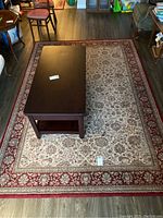 Rug fully visible with dark wood coffee table placed on top, highlighting intricate pattern and colors.