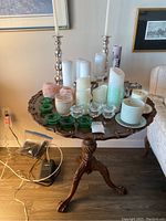 Wooden side table surfaced with assorted candles and candlesticks in a living room setting