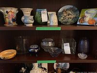 Shelf display including vases, flower frogs, trinket bowl, plate, and ring holder.