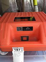 Closed orange molded plastic carrying case with top-lid latch, label reading 'SiteBOSS'