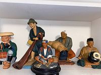 Full view of the five Japanese Hakata ceramic figurines arranged in a row on a white shelf. Features detailed facial expressions and traditional costumes.