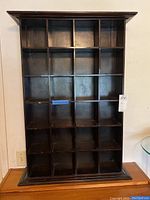 Front view of the dark wood shelving unit showing 24 square compartments in a 4x6 grid with a dark finish.