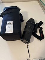 Lens and padded carrying case with strap on white surface