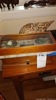 Side view of Henry Troemner scale in glass wooden case with brass weighing pans and a large sea shell behind.