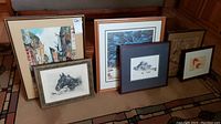 Overview of six framed wall art pieces of varied subjects and sizes, showing condition and framing styles.