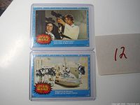 Photo of two 1977 Star Wars Series 1 trading cards in protective cases, numbered #65 and #29.