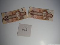 Two circulated Canadian $2 bills showing front side with Queen Elizabeth II portrait and denomination.
