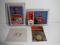 Three items: two Jacques Plante hockey cards and a Hall of Fame medallion in packaging with a handwritten lot number card '153'.