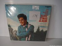 Front album cover of Elvis Presley Elvis' Christmas Album LP record showing Elvis smiling, with text reading Elvis Sings Christmas Songs and ELVIS' XMAS ALBUM in red, issued by RCA Camden in mono format, dated 1970.