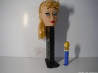 Photo showing the large Barbie head Pez dispenser next to the small Homer Simpson Pez dispenser for size comparison.