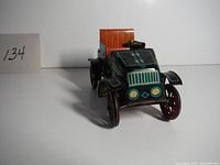 Front view of old pressed steel toy car showing front grill, headlights, and orange seating.