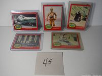 Five original 1977 Star Wars Series 2 trading cards laid out on a surface, each in clear protective sleeves, showing characters and scenes from the classic movie.