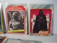 Close-up of three Darth Vader trading cards in protective sleeves showing distinctive Star Wars logos and imagery.