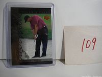 Image of Tiger Woods rookie card in protective sleeve showing front of card with Woods in golfing pose.