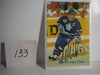Signed photo of Wendel Clark from Toronto Maple Leafs hockey team, showing autograph and player in action.