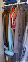Coats and jackets hanging on a rack, showing multiple items in the lot including leather and fabric coats and jackets