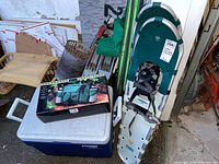 Wide angle photo of lot showing cooler, Adventure Trail Pack box, and pair of Tubbs snowshoes leaning against wall.