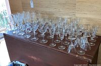 Multiple crystal stemware glasses arranged on a wooden surface, showing four sizes with etched floral décor.