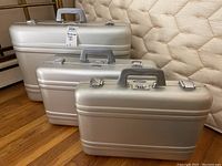 Three silver aluminum cases of varying sizes arranged on floor