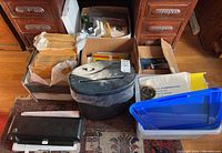 Photo showing paper shredder, boxes with bubble mailers, and some office supplies in bins and trays.