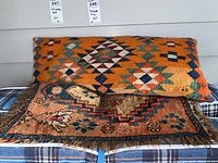 View of the long rectangular pillow behind the small square rug showing the geometric patterns and colors