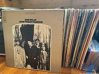 Front cover: Bob Dylan – John Wesley Harding album at left, row of record spines to right