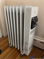 Full front and side view of white Delonghi oil-filled radiator space heater with visible dust and scratches.