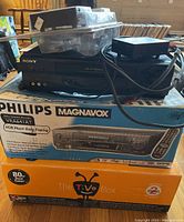 Magnavox VRA64IAT VHS player in box with Sony SLV-N55 VHS player sitting on top and TiVo box below.