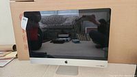 Front view of Apple iMac all-in-one with stand, reflective display and overall condition.