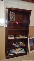 Front view of the wooden bookcase with books and papers placed on the shelves, showing size and structure.