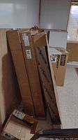 Five tall cardboard boxes standing upright with ceiling tiles, one box labeled USG.