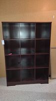 Front side view of the cubby cabinet showing all 12 cubbies arranged in a 3x4 grid with a dark laminated finish.