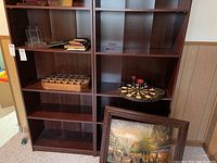 Shelf with golf ball collection in a wooden holder, electric dartboard with darts, empty frames, and other items