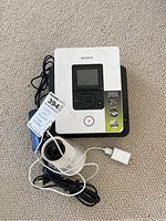 Sony multi-function DVD recorder with a small LCD screen, control buttons on the top, and stickers describing features. USB camera with cables and power adapter placed on top of the recorder.