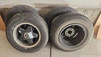 Four black Jaguar rims with tires mounted, showing sidewall and tread of tires.