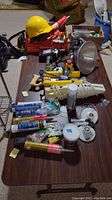 Photo of the entire lot arranged on a table showing a variety of remodeling tools including drill, caulking guns, hard hat, clamps, and tubes of sealants.