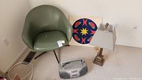 Green vinyl swivel chair with metal three-legged base showing wear and tears on seat cushion