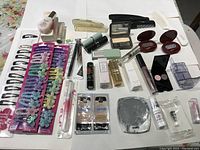 Overview of various new hair clips and assorted beauty products including nail polish, lip gloss, lipstick tubes, eyeshadow compacts, and small fragrance bottle.