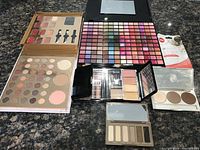 Top overview showing five makeup palettes and anti-aging powder sachet on countertop, various neutral, pink, purple shades visible.