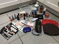 Overall view of nail beauty items and blue flower soap sets on the floor including nail polishes, nail art stickers, nail powder, tools, pouches, and soap cases