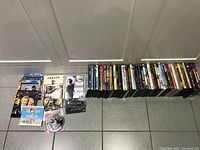 Photo showing a large collection of DVD movies arranged in two rows on tiled floor, titles visible.