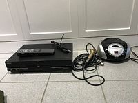 Black DVD player with remote and wired karaoke microphone next to a portable disc player