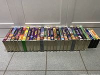Side view of full collection of 20 Disney VHS tapes showing colorful illustrated spine covers and titles