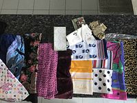 Entire lot of various lady scarfs and wraps displayed on black surface