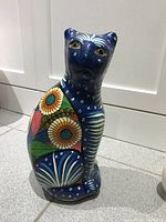 Front view of hand painted cat figurine showing floral designs and cat face