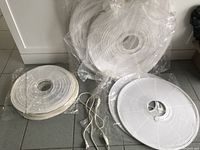 Four white paper lanterns of different sizes laid on the floor with one included switch and electrical cord.