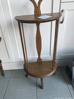 Full view of vintage half-round two-tier side table showing top tier, middle spindles, and legs.
