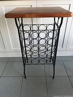 Full view of the wine holder table showing wooden top and black metal circular wine holders.