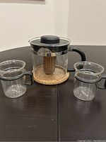 Bodum tea pot on cork coasters with two Bodum glass cups on table, showing entire set.