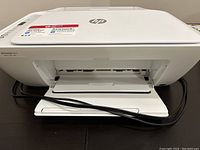 Front view of HP DeskJet 2655 printer on a desk with power cable visible.